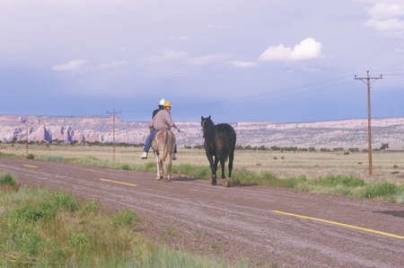 Two Native American teenagers on horseback pulling another horseのeditorial素材