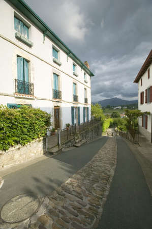 Path between homes in Sare, France in Basque Country on Spanish-French border, a hilltop 17th century village in the Labourd province. The houses are built in the traditional style of the region, with shutters painted colors red and green of the Basque flのeditorial素材
