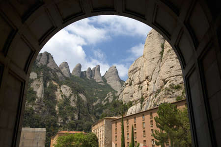 Arch view of jagged mountains in Catalonia, Spain, showing the Benedictine Abbey at Montserrat, Santa Maria de Montserrat, near Barcelona, where some feel the Holy Grail had beenのeditorial素材