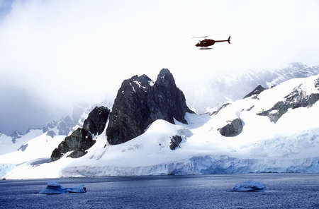 Helicopter patrolling over glaciers and icebergs in Errera Channel at Culberville Island, Antarcticaのeditorial素材