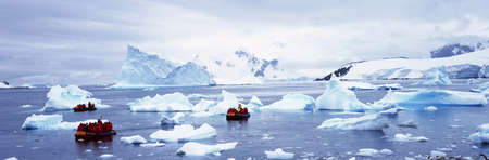 Panoramic view of ecological tourists in inflatable Zodiac boat with glaciers and icebergs in Paradise Harbor, Antarcticaのeditorial素材