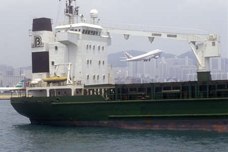 Freighter ship in Hong Kong Harbor and passenger jet at take-off