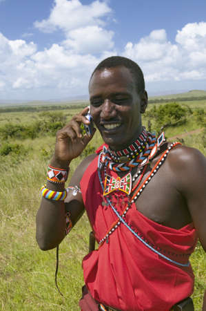 Masai in red toga talks on his cell phone from the grasslands of the Lewa Wildlife Conservancy in North Kenya, Africaのeditorial素材