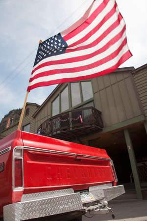 US Flag flies over old red chevrolet pickup truck, July 4 Independence Day Parade, Ouray, Coloradoのeditorial素材