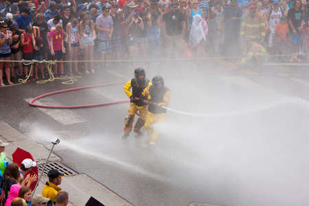 Men dressed in yellow firemen slickers and firehoses have annual Waterfight on July 4, Main Street,...