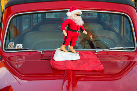 Surfing Santa Clause on a vintage red car hood, California, USAのeditorial素材