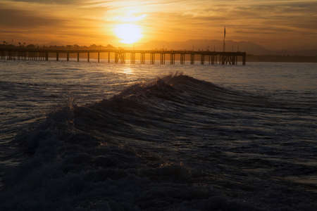 Ocean waves at sunrise with Ventura Pier, Ventura, California, USAの写真素材