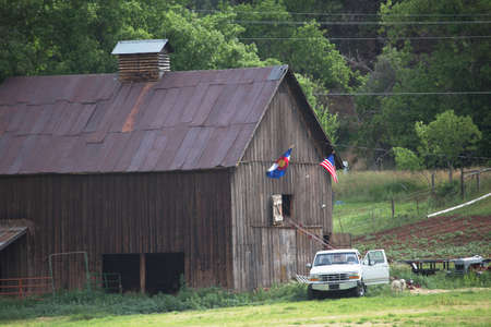 Colorado and US Flag hang on barn with white pickup truck, Colorado, USAのeditorial素材