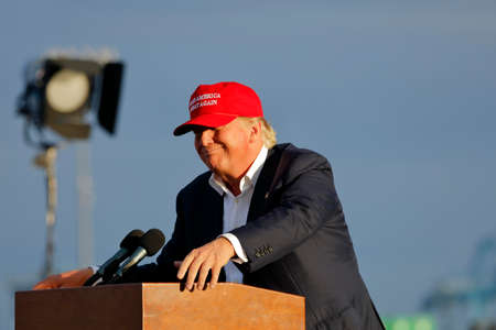 SAN PEDRO, CA - SEPTEMBER 15, 2015: Donald Trump, 2016 Republican presidential candidate, speaks during a rally aboard the Battleship USS Iowa in San Pedro, Los Angeles, California while wearing a red baseball hat that says campaign slogan Make America G