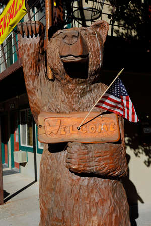 Carved wooden bear and US Flag waves with paw and Welcome Sign, Ouray, Coloradoのeditorial素材