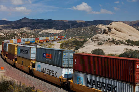 Freight train with cargo containers winds its way through mountain landscape, California