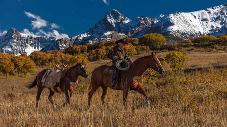 OCT 4, 2017, RIDGWAY COLORADO - Older Cowboy, Howard Linscott , leads packhorse across historic Last Dollar Ranch on Hastings Mesa, SW Colorado, San Juan Mountainsのeditorial素材
