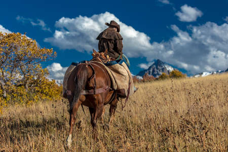 OCT 4, 2017, RIDGWAY COLORADO - Older Cowboy, Howard Linscott , leads packhorse across historic Last Dollar Ranch on Hastings Mesa, SW Colorado, San Juan Mountainsのeditorial素材