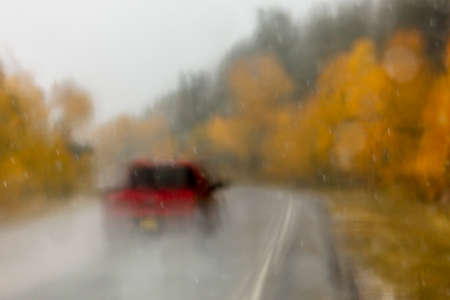 OCTOBER 8, 2018 USA - Colorado/New Mexico Highway 17 in rain - Red pickup truck drives in rain road dotted with autumn colored yellow treesのeditorial素材