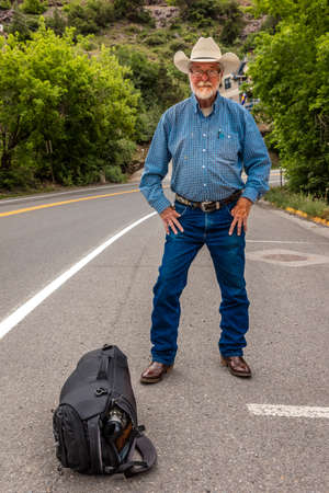 July 20, 2018, OURAY COLORADO, USA - Cowboy hitch hikes along route 550 outside of Ouray, Coloradoのeditorial素材