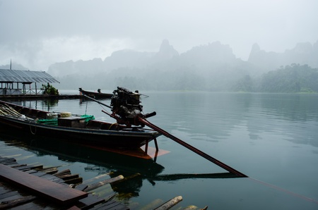 motorboat in lake against foggy mountain in thailandの写真素材