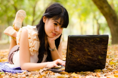 asian girl playing laptop in gardenの写真素材