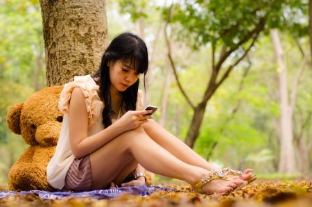 asian girl playing cell phone in gardenの写真素材
