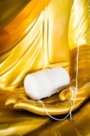 hand of buddha statue holding a role of white lineの写真素材