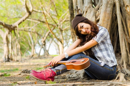 beautiful lady sitting under the tree with ukuleleの写真素材