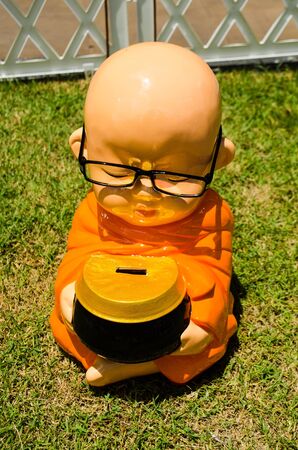 minifigure kid monk meditating on green grass with alms bowlの写真素材
