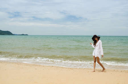 beautiful asian lady wearing white shirt walking on the beachの写真素材