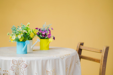 plastic flower in blue pot on against yellow wallの写真素材