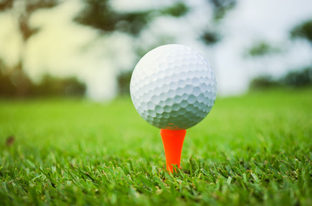 golf ball with orange tee on green grassの写真素材
