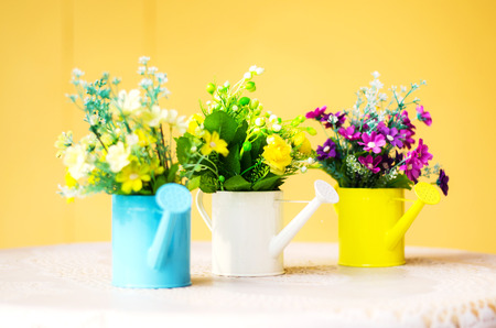 plastic flower in blue pot on against yellow wallの写真素材
