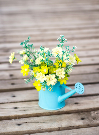 plastic flower in blue pot on against yellow wallの写真素材