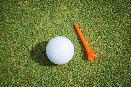 golf ball with orange tee on green grassの写真素材