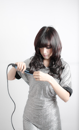 woman joyful with her hair straightenerの写真素材