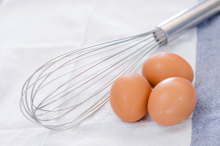 three eggs with eggbeater on fabricの写真素材