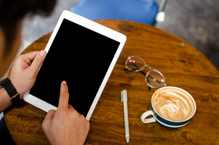 man using tablet on wooden table