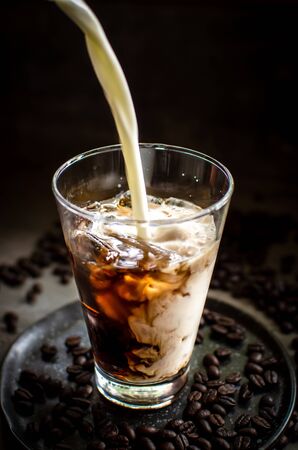 milk being pour into iced espresso in low-key