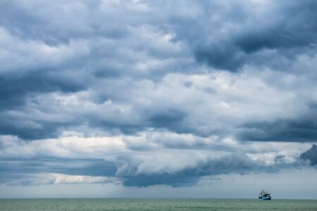 small fishing boat in open sen against cloudy weather