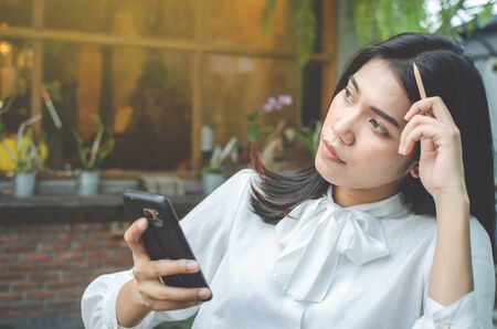 business woman in white shirt using smartphone in cafeの写真素材