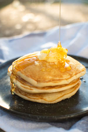 honey being pour onto stack of pancake