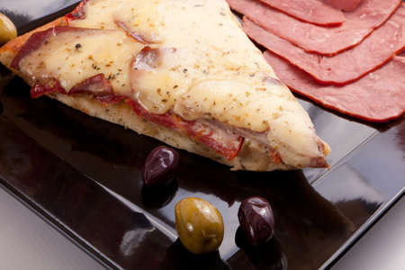 A Slice of supreme pizza being lifted up with olive の写真素材