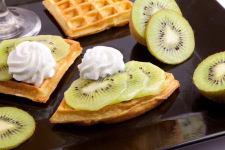 Kiwi Tart Slices with fresh vanilla cream on black dishの写真素材