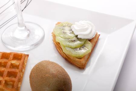Kiwi Tart Slices with fresh vanilla cream on white dishの写真素材