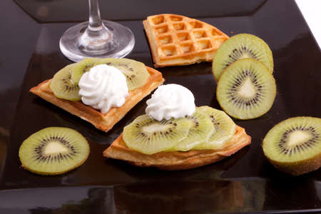 Kiwi Tart Slices with fresh vanilla cream on black dishの写真素材
