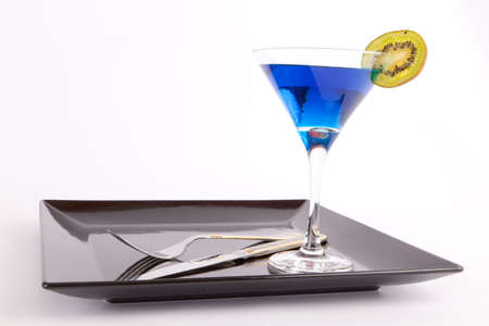 Blue drink in a cocktail glass in black dish with fork and knife の写真素材