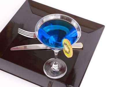 Blue drink in a cocktail glass in black dish with fork and knife の写真素材