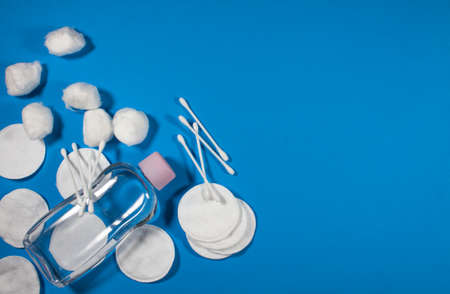 personal hygiene items cotton pads, lotion, cotton buds on a textured blue background. top view with space for textの写真素材