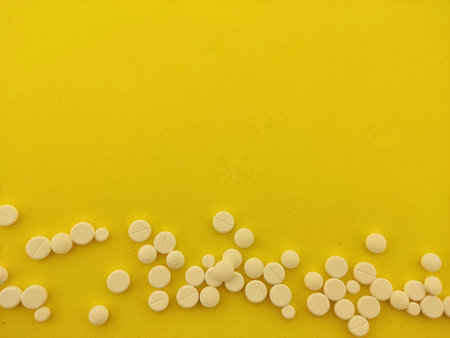 a lot of white pills on a yellow background located at the bottom, the concept of medicineの写真素材