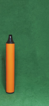 orange electronic cigarette for smoking light smoke, on a green backgroundの写真素材