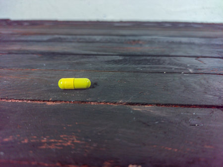 Yellow pill on wood table. Medicine and health care concept background.の写真素材