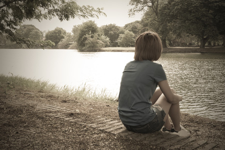 women sadly,sit at the waterfront with a lonely atmosphere.の写真素材