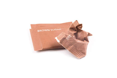 Intact and crumpled packaging of brown sugar. Isolated white background. Concept of cutting down sugar intake.の写真素材
